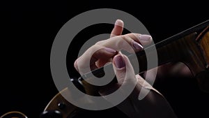 Close up fingers of a musician sifting the violin . Black background