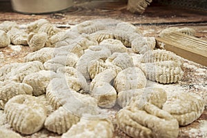 Close-up of finished raw fresh gnocchi on wooden background with manual gnocchi maker