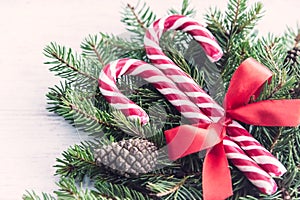 Close up of a fir tree and candy cones tied with a red bow over an old white wood background. Christmas decoration background.