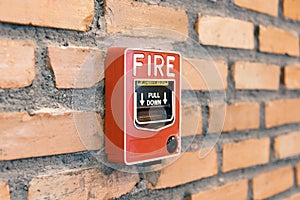 Close up fire alarm activation box on brick wall in room