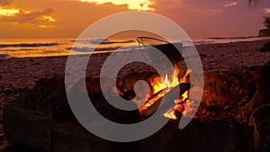 CLOSE UP: Fire burns on tropical white sand shore of Barbados on sunny evening
