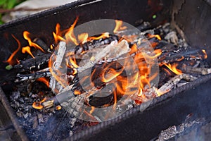 Close up of fire on chargrill. Dry sticks smoulder. Concept of cooking on grill