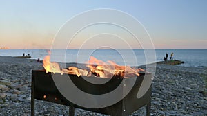 Close-up fire in the grill on the seashore, picnic on the beach