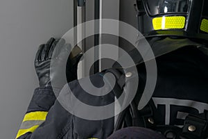 Close-up of a firefighter, rear view, looking out the dark window of a metal door, leaning on his arm