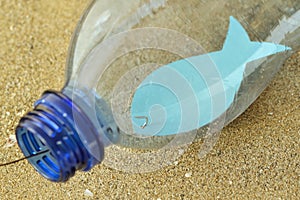 Close-up of fish on a hook in a plastic bottle - Concept of ecology and stop plastic pollution