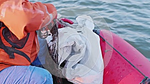 Close up of fishermans hands and legs who pulls fishing net out of water of Kara sea. Net is full of sea weed and a bit