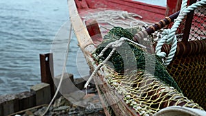 Close-up of fishing boat on wooden pier. Clip. Fishing nets on wooden boat standing on sea pier. Beautiful details of