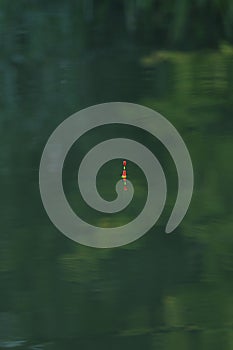 Close-up of fishing gear in the water with reflection, the texture of the water is green. A background image of the water surface