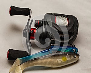 Close up of fishing reel and lures on a plain background