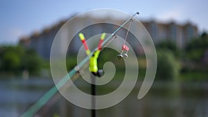 Close-up fishing sinker on fishing pole outdoors in urban park with blurred city at background. Fishing rod on sunny