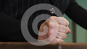 Close-up of a fist in slow motion hitting the table. Fist bump on pulpit, table, wooden surface.