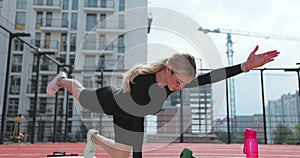 Close up of fit sport woman is doing warm-up on a basketball court gymnastic rug and raises her legs and arms