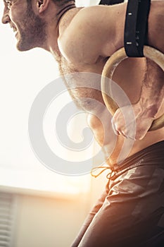 Close up Fitness handsome man doing dipping exercise using rings in the gym
