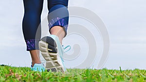 Close up of fitness woman athlete`s running shoes while walking in the park outdoor. Sport, healthy, wellness and active lifestyl