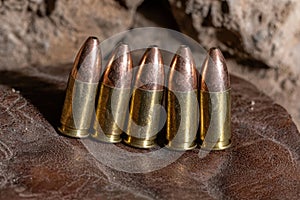 Close-up of five bullets on brown leather