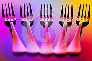 Close up of five stainless steel forks on abstract background with reflections