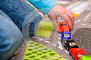 Close-up of five year old boy playing and lining up toy cars holding a red pickup truck