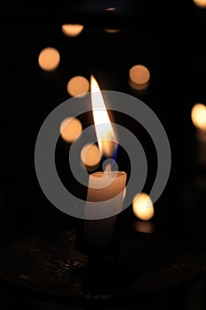 Close-up of the flame of candle in the dark in church with bokeh background.
