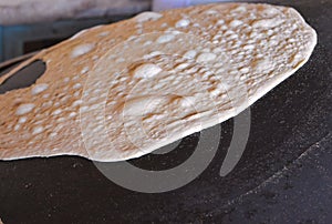 arabic bread called Markook in lebanon, being cooked on a convex iron plate.