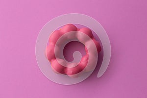 Close up flat lay of pink pon de ring on pink background.