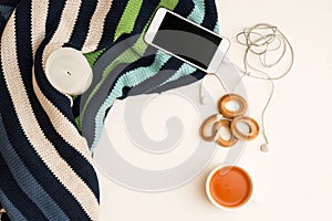 Close up, flat lay, top view. Autumn mood in the office. Warm sweater, orange tea, telephone with headphones. White background