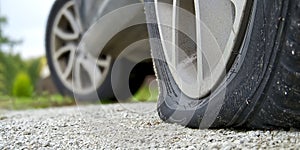 Close-up of Flat rear tire on car. The right rear broken weel. Damaged rear wheels on parking place