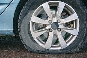 Close up of a flat tire of a blue car on road