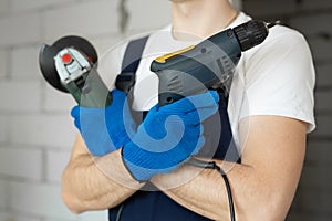 Close-up of a flex and a tile cutter in the hands of a male builder.