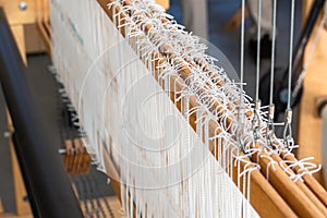 Close-up of a floor loom warp threads and heddles for textile weaving