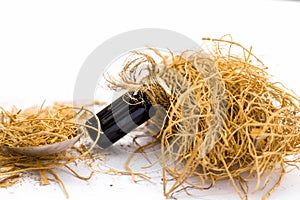 Close up of floral and ayurvedic essence or essential oil of khus or vetiver or vevtier grass in a small glass bottle isolated.