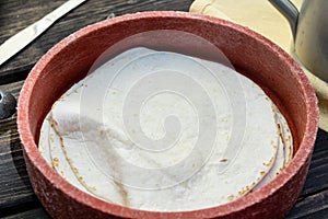 Close up of flour tortillas in red plastic bowl