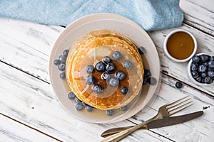 Close up of fluffy pancakes with maple syrup and blueberries.