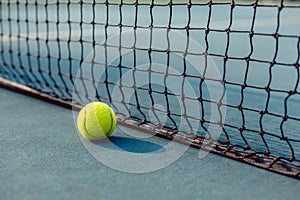 Close-up of a fluorescent yellow ball in front of the net of a tennis court