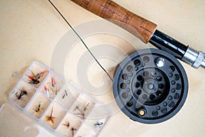 Close up of fly fishing rod with reel next to box with tied flies. Fly fishing equipment still life. Nobody