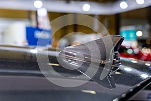 Close up of an FM AM GPS Navigation antenna placed on the roof of a vehicle.  Blurry defocused background