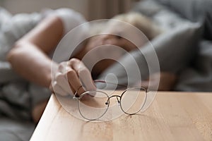 Close up focus on eyeglasses on wooden bedside table.