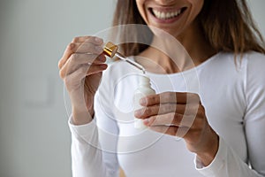 Young woman holding bottle with collagen moisturizer face serum photo