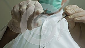close-up in focus the surgeon`s hands are holding a surgical instrument, the doctor`s hands with a scalpel approach and go out of