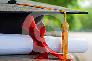 Close up focus of university graduate holds degree certificate and graduation cap celebrates in the  graduation ceremony.