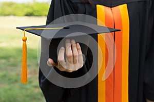 Close up focus of university graduate holds degree certificate and graduation cap celebrates in the  graduation ceremony.