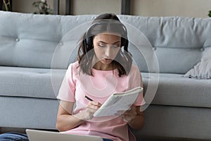 Close up focused Arabian woman in headphones taking notes