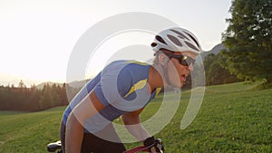 CLOSE UP: Focused cycling athlete pedaling up a sunny road in the countryside.