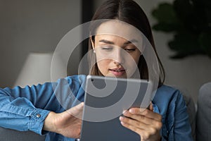 Close up focused woman looking at tablet screen, chatting online