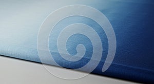 A close-up of folded blue fabric with a gradient effect, transitioning from light to dark