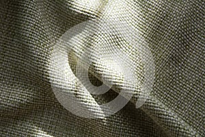 Close-up of a folded green synthetic fabric with a large thread