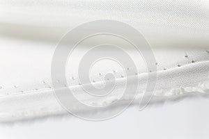 Close up of folded shiny white fabric showing fabric`s edge