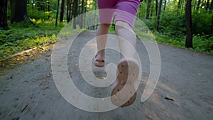 Close up follow handheld close up of children feet running through park forward towards light from sun. happy little