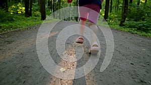 Close up follow handheld close up of children feet running through park forward towards light from sun. happy little