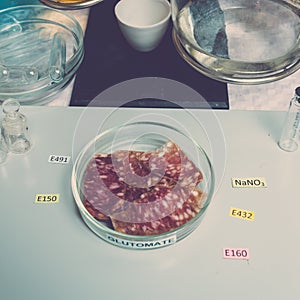 Close up food additives in sausages. Additives are on the table next to the sliced sausage in the lab. Unhealthy food concept