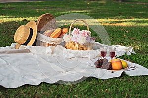 Close up of food drinks and a picnic basket on blanket in the grass in a summer park. Concept of leisure and family